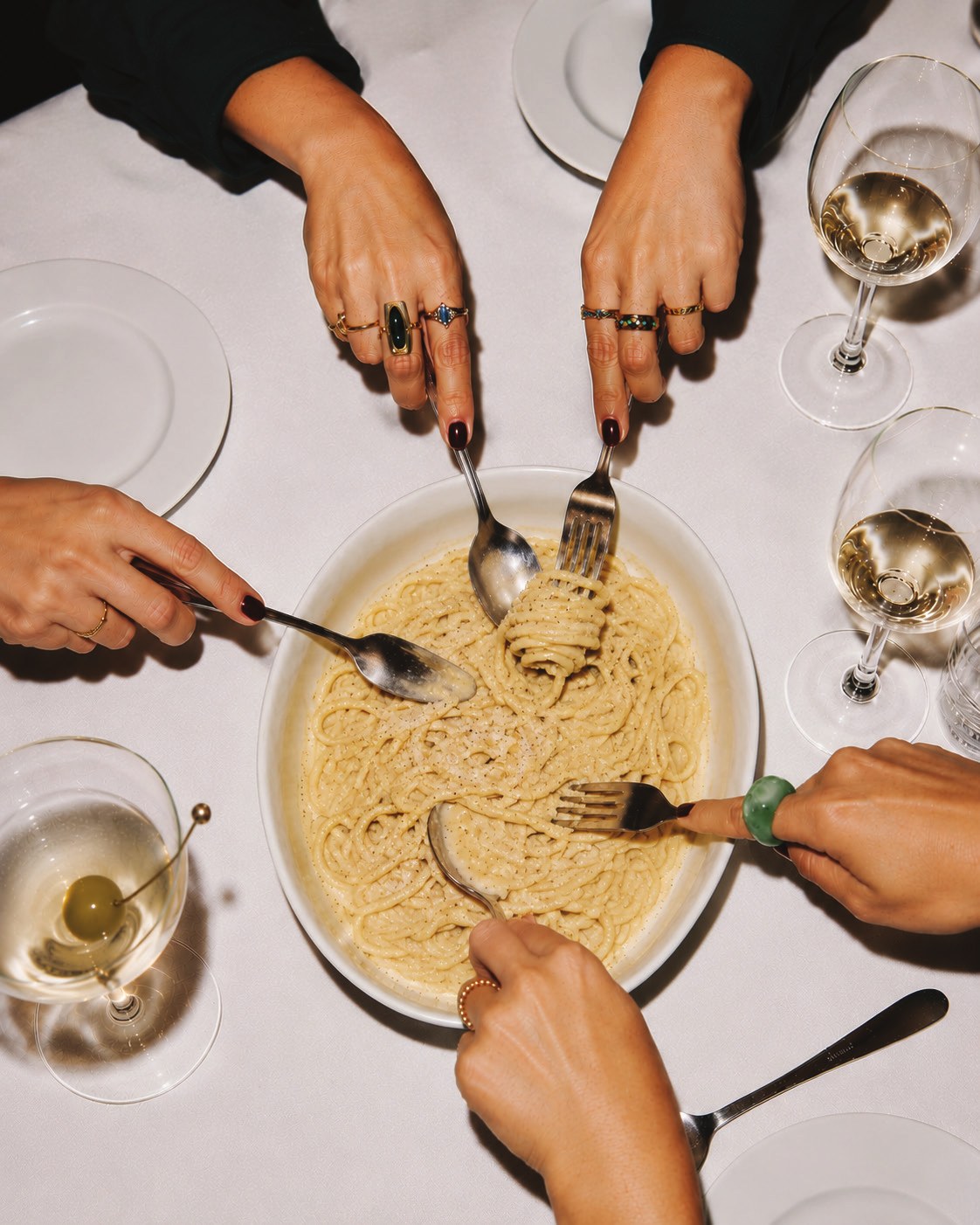 Personas compartiendo un platillo de pasta en la mesa